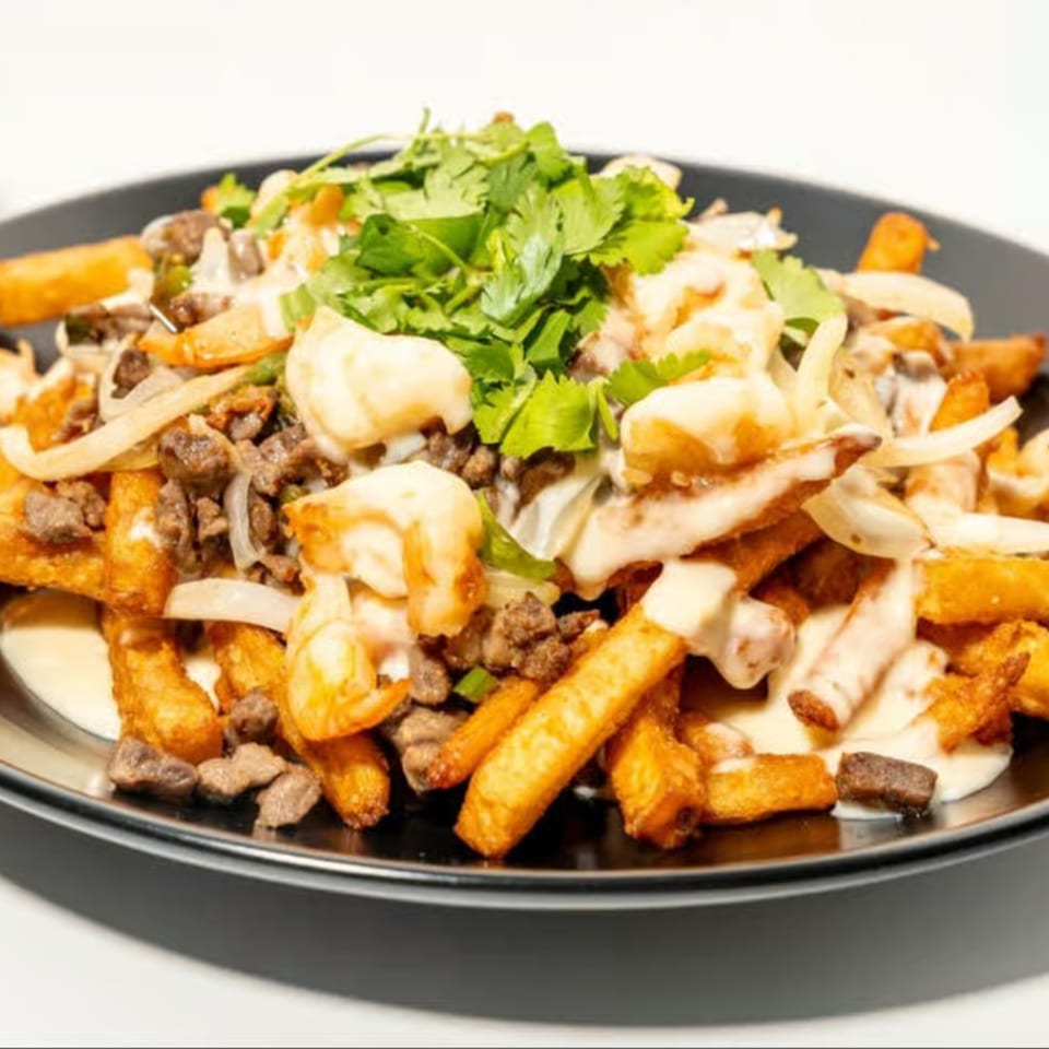La Familia's Mexican fries topped with steak, shrimp, onions, creamy sauce, and cilantro.