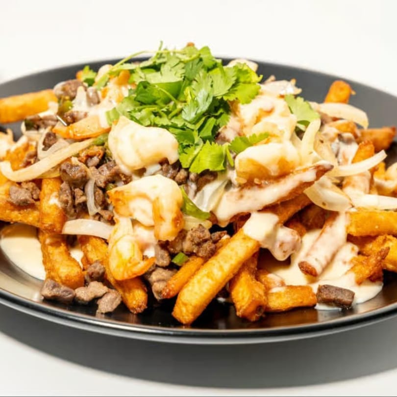La Familia's Mexican fries topped with steak, shrimp, onions, creamy sauce, and cilantro.